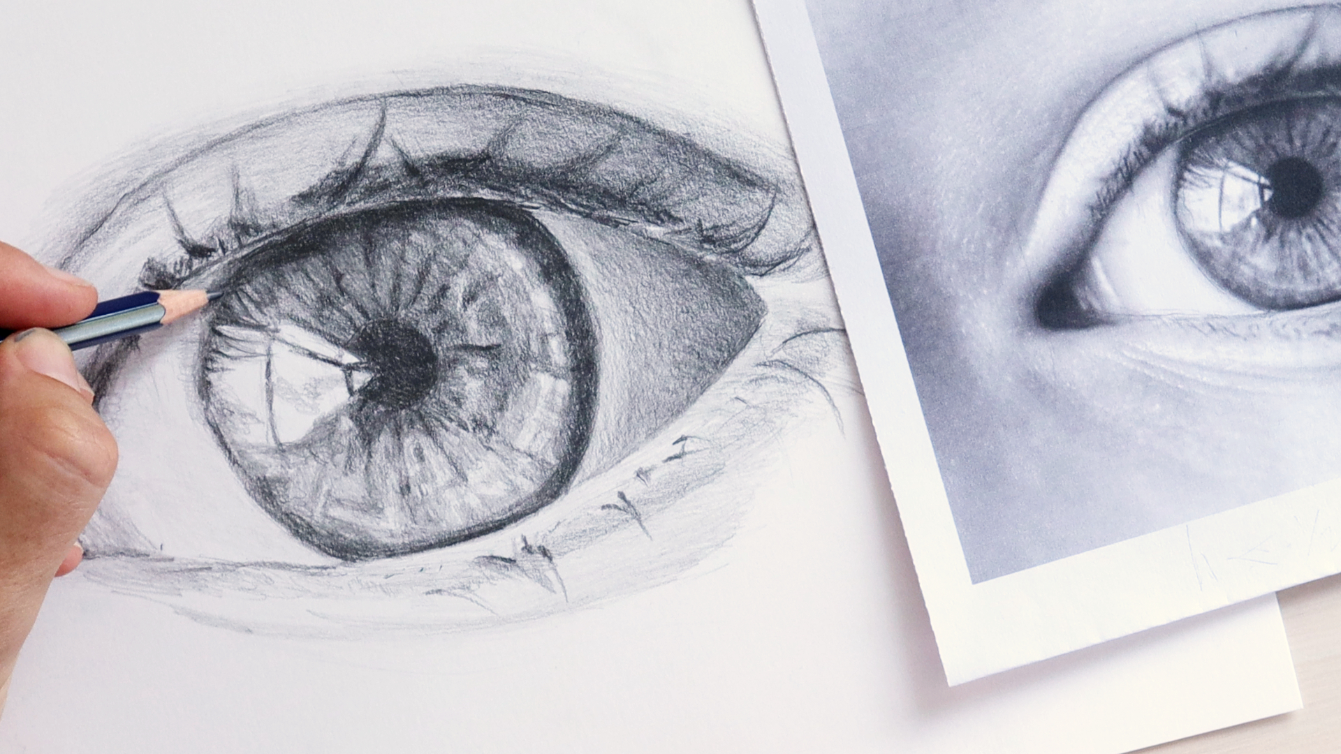 Image showing a hand sketching a realistic eye drawing from a photograph