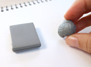 photo showing unused kneadable eraser square next to a hand holding an eraser kneaded to the shape of a ball