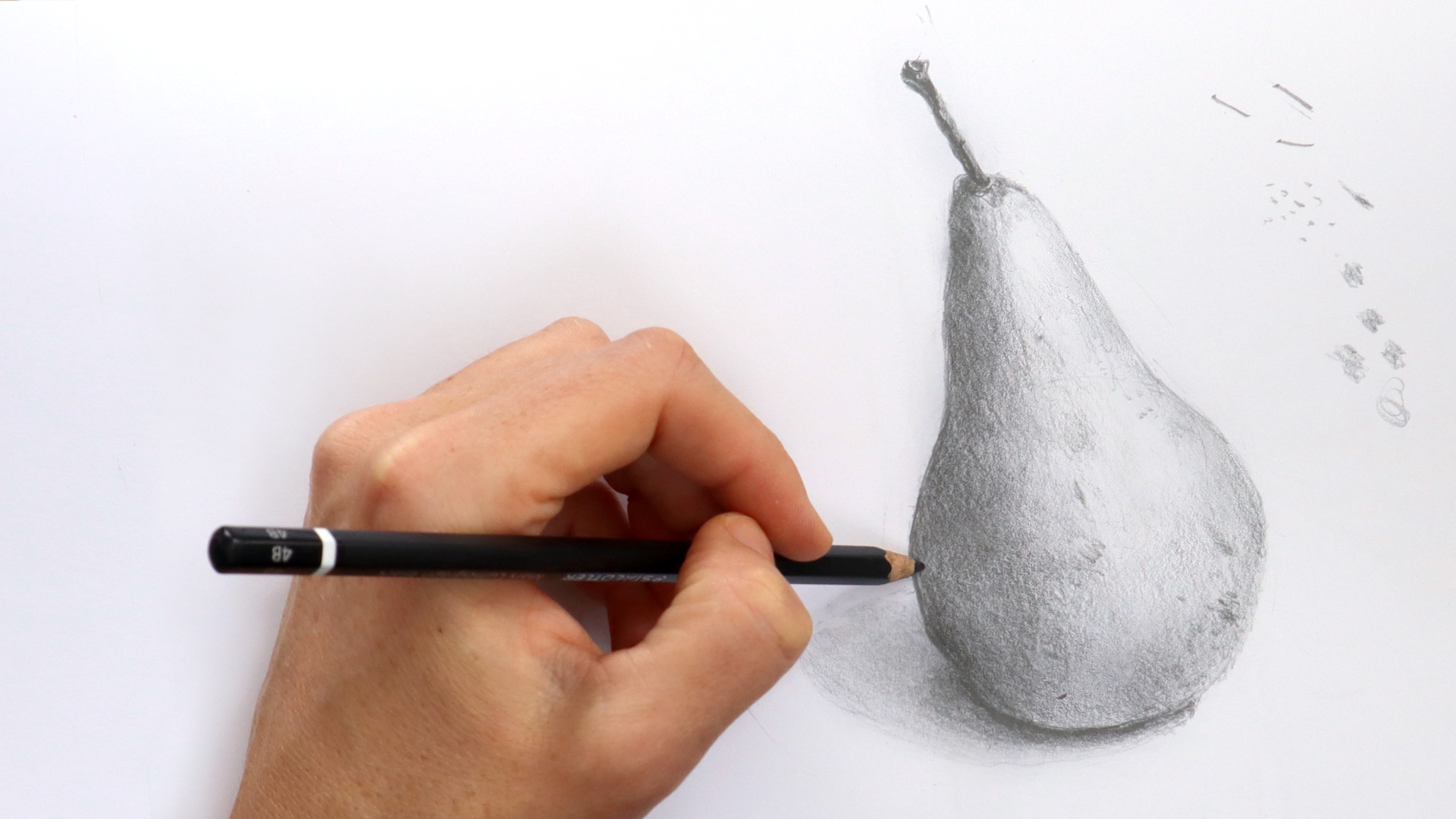 image showing a hand holding a pencil and sketching a pear